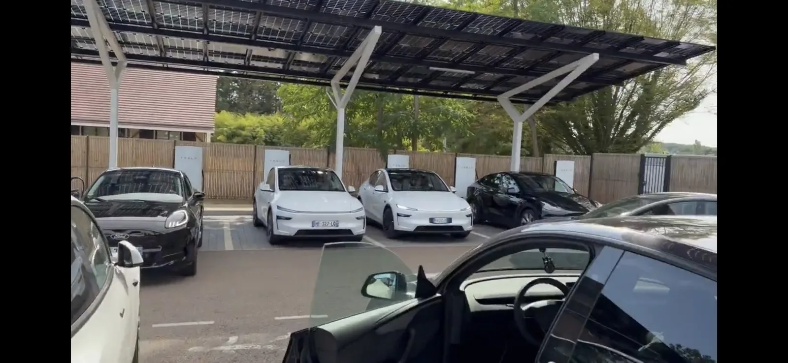 Teslas laden an einem Supercharger unter einem Solardach